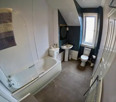 a bathroom with a large tub and a sink at Hunters Guest House in Brodick