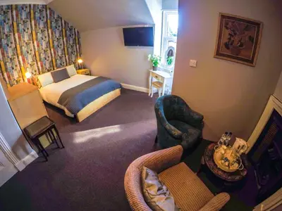a hotel room with a bed and a chair at Hunters Guest House in Brodick
