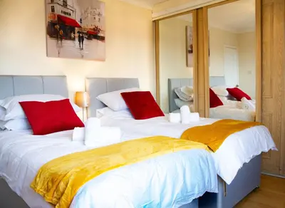 a bedroom with two beds with red and white pillows at Carvetii - Derwent House - Spacious 2nd floor flat in Grangemouth