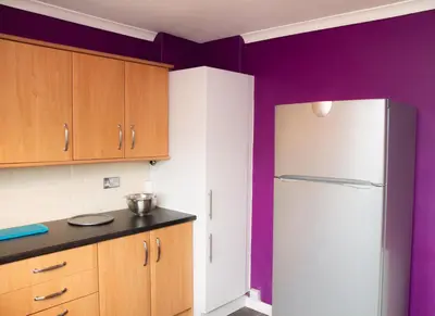 a kitchen with purple walls and a refrigerator at Carvetii - Derwent House - Spacious 2nd floor flat in Grangemouth