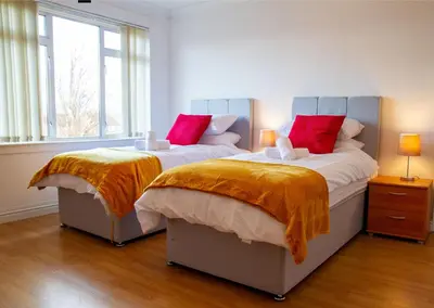 a bedroom with two beds with red and yellow blankets at Carvetii - Derwent House - Spacious 2nd floor flat in Grangemouth