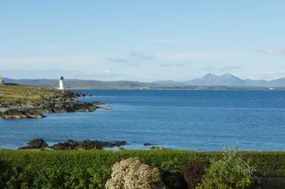 a lighthouse on the shore of a large body of water at Killinallan Cottage in Port Charlotte