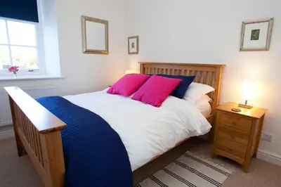 a bedroom with a large bed with two pink pillows at Saligo in Port Charlotte