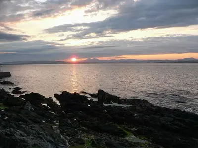 a sunset over a large body of water at Sanaigmore Cottage in Port Charlotte