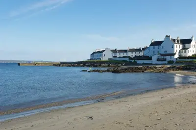 a group of white houses on the shore of a beach at Kilchoman in Port Charlotte