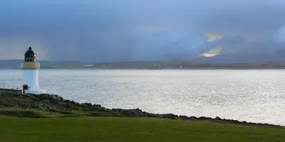 a lighthouse sitting on the edge of a body of water at Ardnave in Port Charlotte
