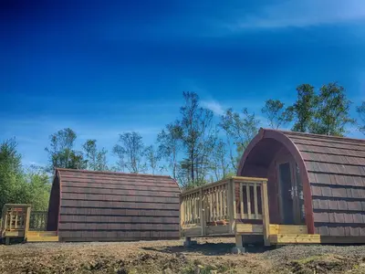 two large wooden huts sitting next to each other at Tarbert Holiday Park in Tarbert