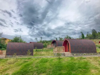 two huts in a field with a cloudy sky at Tarbert Holiday Park in Tarbert