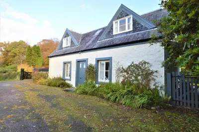 a white house with a black roof and a driveway at Darroch Beag in Saint Catherines