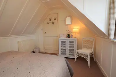 a bedroom with a bed and two chairs in a attic at Darroch Beag in Saint Catherines