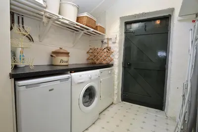 a laundry room with a washing machine and a green door at Darroch Beag in Saint Catherines