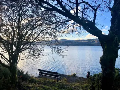 a person sitting on a bench next to a lake at Darroch Beag in Saint Catherines