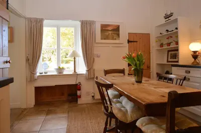 a dining room with a table and chairs and a window at Darroch Beag in Saint Catherines