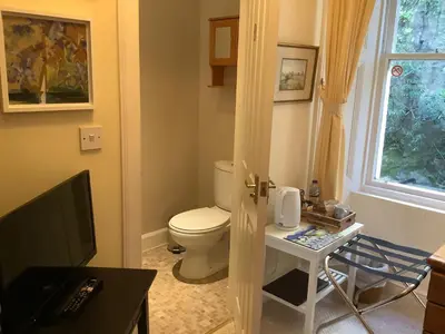 a bathroom with a toilet and a table with a television at Struan House B&B in Tarbert