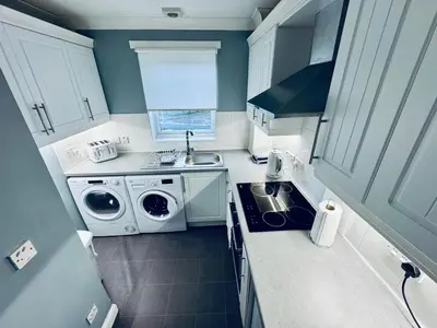 a small kitchen with a washing machine and a sink at Modern 2 bedroom Apartment Near City Centre in Glasgow