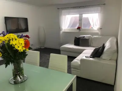 a living room with a couch and a table with flowers at Modern 2 bedroom Apartment Near City Centre in Glasgow