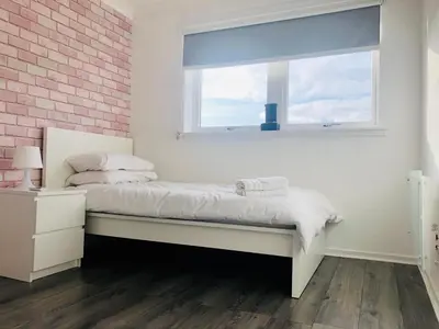 a white bedroom with a bed with a window at Modern 2 bedroom Apartment Near City Centre in Glasgow