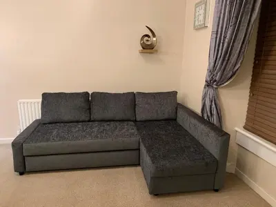 a couch sitting in a living room next to a window at Dunfermline GF flat, 5 min walk to Train St. and High St. in Dunfermline