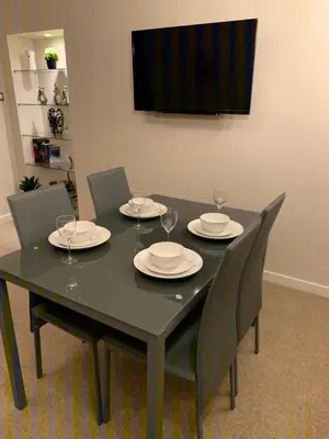 a black table with chairs and plates and wine glasses at Dunfermline GF flat, 5 min walk to Train St. and High St. in Dunfermline