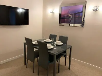 a black dining room table with chairs and a television at Dunfermline GF flat, 5 min walk to Train St. and High St. in Dunfermline