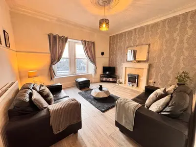 a living room with two couches and a fireplace at THE LION’S REST - BOUTIQUE APARTMENT SUITE. in Port Glasgow