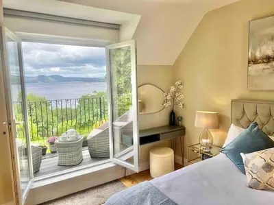 a bedroom with a large window with a view of the ocean at Loch View at Lomond Castle in Balloch