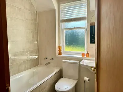 a bathroom with a toilet and a tub and a sink at Loch View at Lomond Castle in Balloch