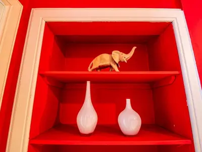 a toy elephant sitting on a red shelf with two vases at Beautiful and Bright Georgian Style Morningside Apartment - Pass the Keys in Edinburgh