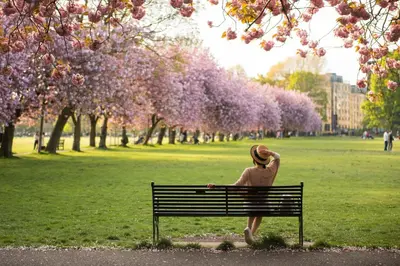 a woman sitting on a bench in a park at Beautiful and Bright Georgian Style Morningside Apartment - Pass the Keys in Edinburgh