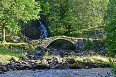 a stone bridge over a river with a waterfall at Chesthill House and Estate, Glen Lyon in Aberfeldy