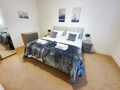 a bedroom with a large bed with two night stands at Linburn House Apartment in Dunfermline