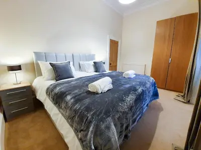 a bedroom with a large bed with two towels on it at Linburn House Apartment in Dunfermline
