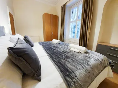 a bedroom with a large bed with pillows and a window at Linburn House Apartment in Dunfermline