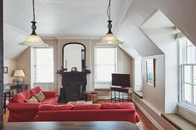 a living room with a red couch and a fireplace at Brambles of Inveraray in Inveraray
