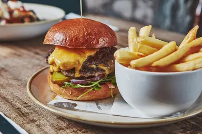 a plate with a cheeseburger and french fries on a table at Brambles of Inveraray in Inveraray