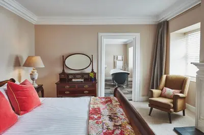 a bedroom with a bed and a chair and a mirror at Brambles of Inveraray in Inveraray