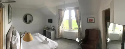 a bedroom with a bed and a chair and a window at The Colintraive in Colintraive