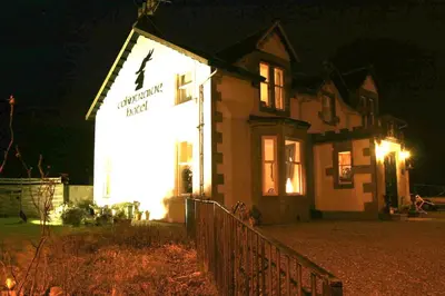 a building with a sign on the side of it at night at The Colintraive in Colintraive