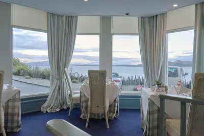 a restaurant with tables and a view of the water at Crinan Hotel in Crinan