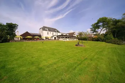 a large white house with a large green field at Lochnell Arms Hotel in Oban