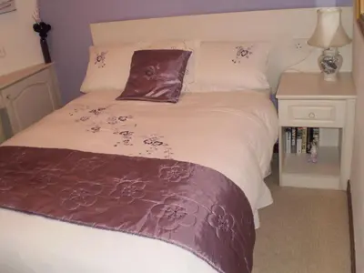 a bed with a brown blanket on top of it at Shawlee Cottage in Airdrie