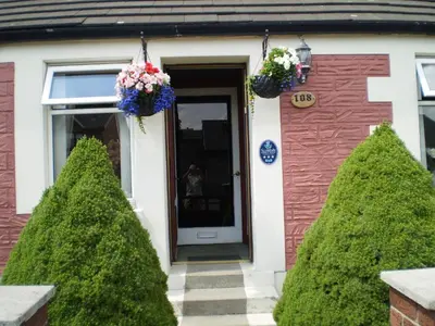 a house with two trees in front of a door at Shawlee Cottage in Airdrie