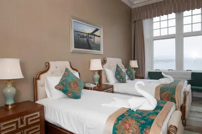 two beds in a hotel room with two windows at The Glenburn Hotel in Rothesay