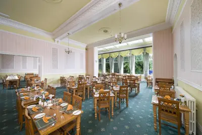 a dining room with tables and chairs and windows at The Glenburn Hotel in Rothesay