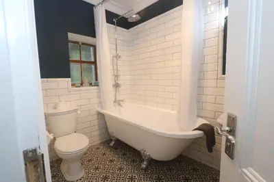 a bathroom with a white tub and a toilet at Charming two bedroom, two bathroom detached cottage in Boʼness