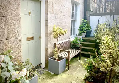 a porch with a bench and some plants and a door at Stylish City Centre Apartment in Edinburgh