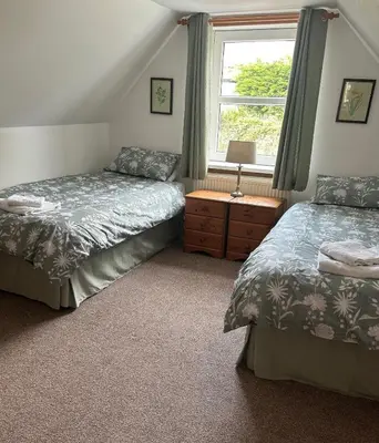 a bedroom with two twin beds and a window at Rowan Cottage in New Galloway