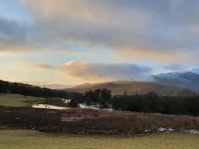 a view of a field with mountains in the background at Ben Ledi View in Callander