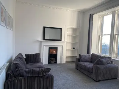 a living room with two chairs and a fireplace at Carvetii - Edward House B - 2 Dbl bed 1st floor flat in Dunfermline