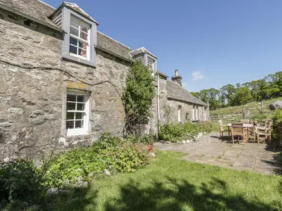 an old stone house with a patio in the yard at Balmeanoch in Lochearnhead